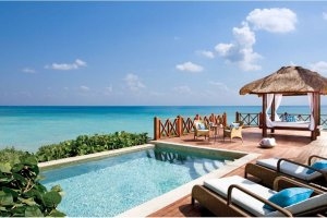 atemberaubender sauberer pool mit kristall klaren blauen wasser und meer blick auf das türkis farbene wasser des ozeans und sonnenliegen davor an der seite eine kleine tiki hut hütte mit strohdach und liegen drin und weissen vorhängen das alles auf einer 